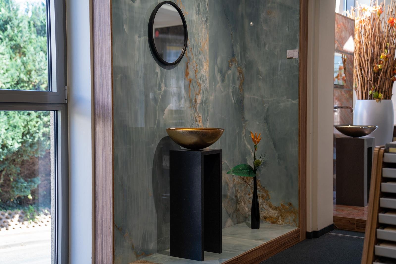 Musterbad mit Fliesen in Marmoroptik und goldenem Waschbecken in der Ausstellung des Pung Fliesen-Centers