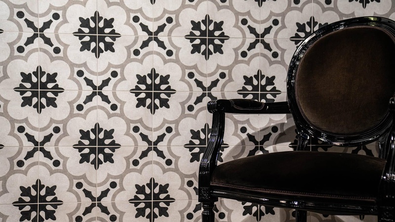 Wandfläche mit schwarz-weißen Ornamentfliesen und Polstersessel im Wohnbereich